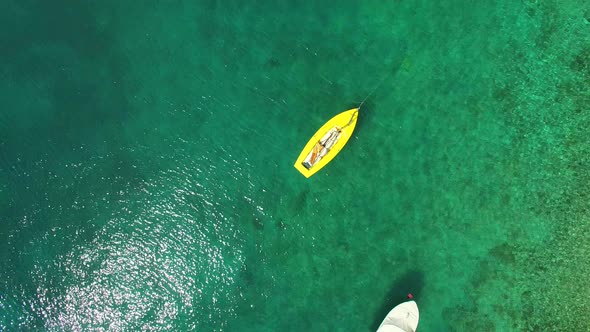 Yellow fishing boat floating in clear green sea alt