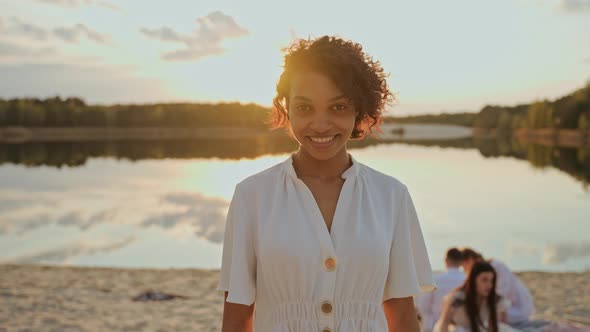Beautiful Young Black Girl Looking at Camera Standing on a Beach at the Sunset