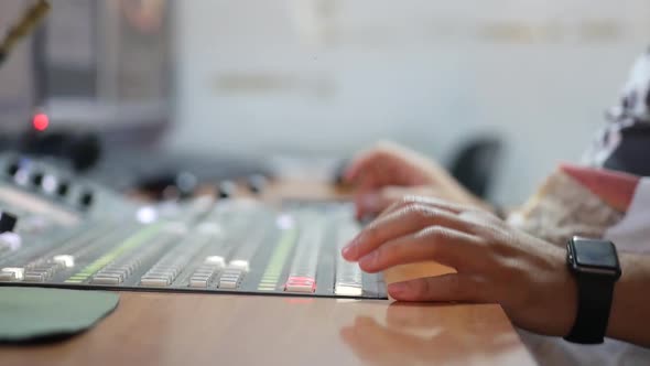 Close-up of a man sitting at a TV control panel for production and broadcasting alt