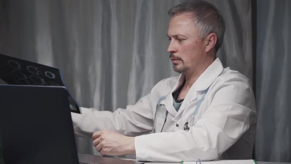 Portraiture of Senior Doctor Examining X-ray. Then Doctor Working with Laptop Computer.