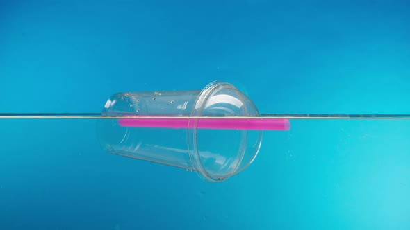 Floating Plastic Glass with a Cocktail Tube in the Ocean Throwing Garbage Into the River or Lake alt