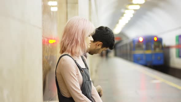 Side View Young Couple Sitting Indoors on Metro Station As Train Leaving in Slow Motion alt