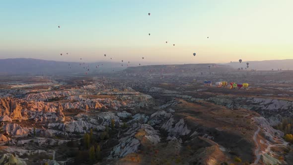 Colorful Hot Air Balloons Flying Over Rocky Landscape in the Morning alt