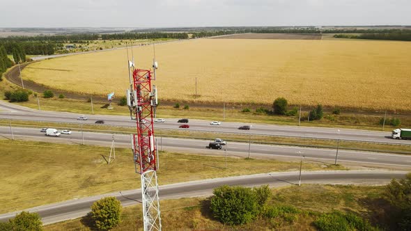 Telecommunication Antenna Receiver Tower Near Highway with Car Traffic alt
