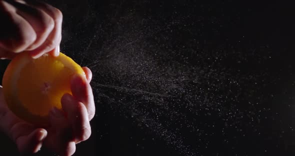 Super Slow Motion Squeeze Juice From Orange Close Up on a Black Background