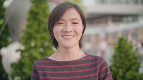 Portrait of attractive smiling asian woman in city