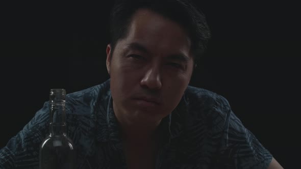 Close Up Of Drunk Asian Man With Vodka Looking At Camera In Black Background alt