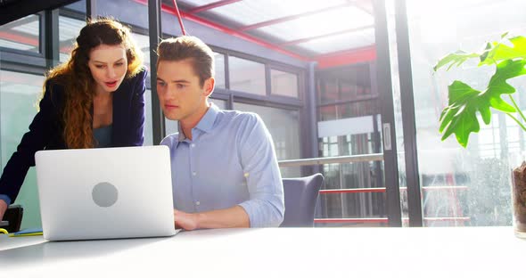 Business executives discussing over laptop alt