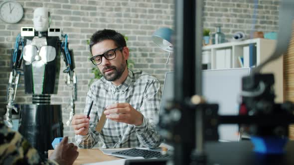 Creative Guys Talking About 3D Printed Elements Pointing at Models in Workplace alt