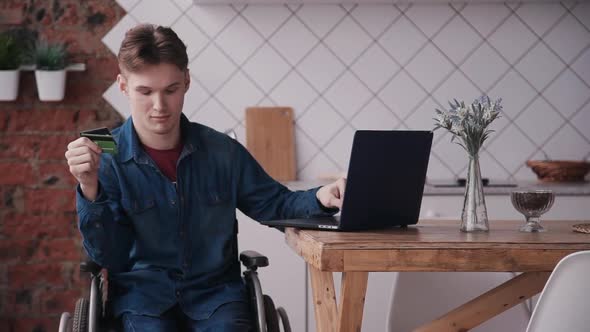 Young Man in Wheelchair Using Laptop and Credit Card