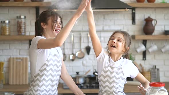 Young Mother and Her Pretty Daughter Having Fun Together at The Kitchen, While Cooking