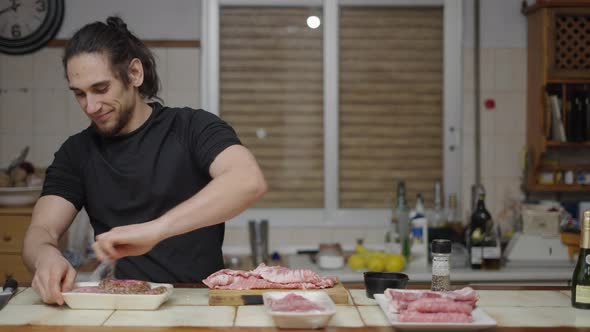 Playful Man Preparing Burger Meat and Making Funny Bite Gestures for the Camera alt