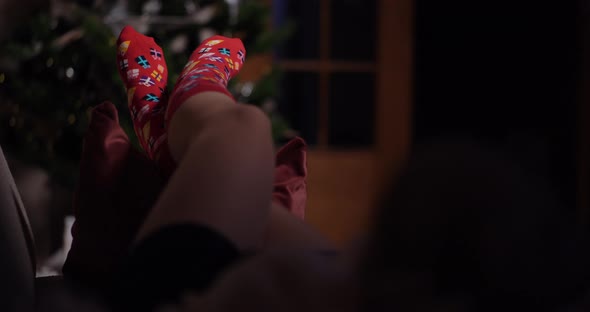 Woman Wearing Warm Wool Socks Lying By the Fireplace at Christmas alt