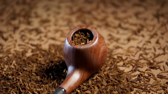 Old fashioned tobacco pipe.Elegant pipe on fabric in the middle of dried tobacco alt