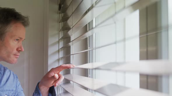 Man looking outside through the window 4k alt