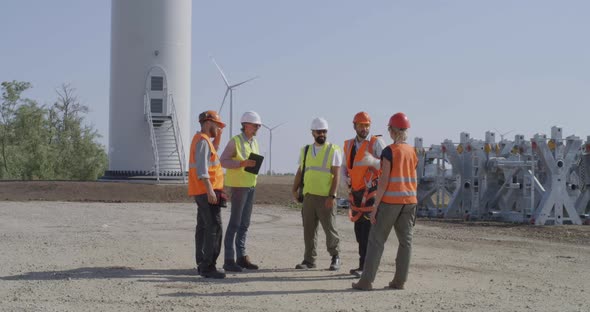 Engineers Inspecting Construction Site Near Windmill alt