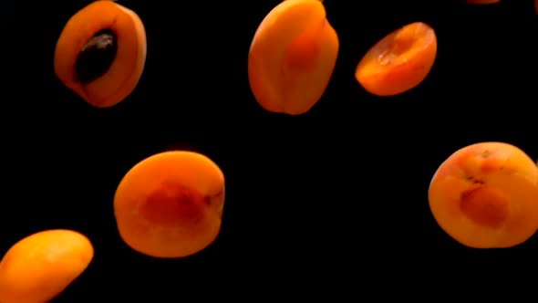 Halves Ripe Apricots Fly on a Black Background alt