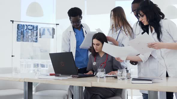 Team of Multi Ethnic Expert Doctors Examining Medical Reports at Hospital. alt