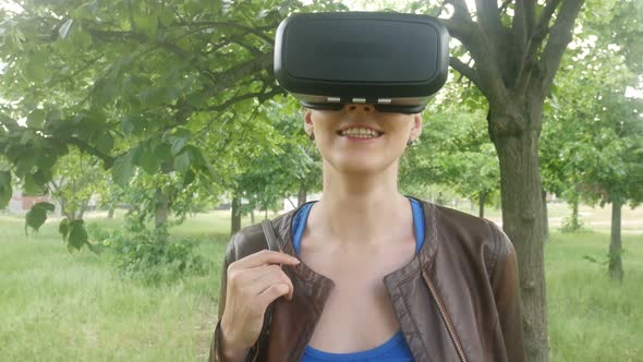 Cheerful Beautiful Woman Uses A Modern Helmet Of Virtual Reality In The Park