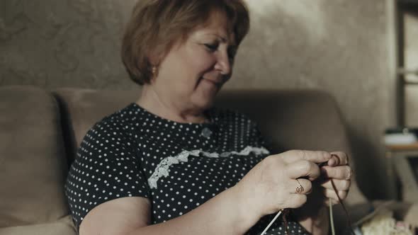 Elderly woman knitting at home  alt