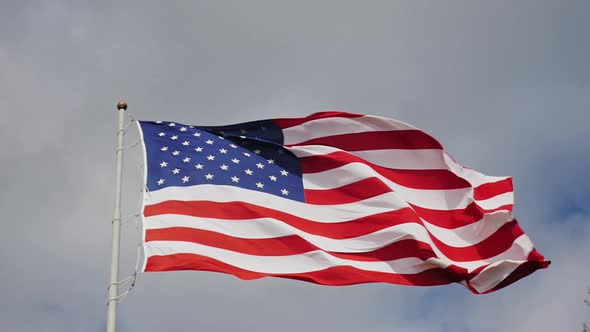Large US Flag on a Background of Gray Sky Beautifully Illuminated By the Sun alt