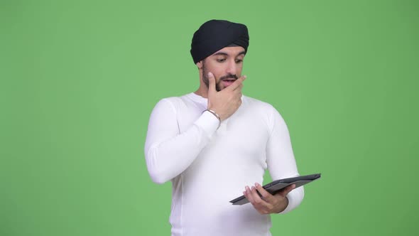 Young Bearded Indian Man Using Digital Tablet and Looking Shocked