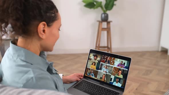 Curly Woman Waving at the Laptop Screen with People Profiles Using an Application alt