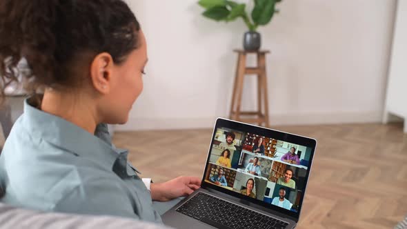 Curly Woman Waving at the Laptop Screen with People Profiles Using an Application