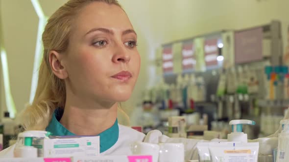 Female Pharmacist Organizing Products on a Shelf, Working at Drugstore t alt