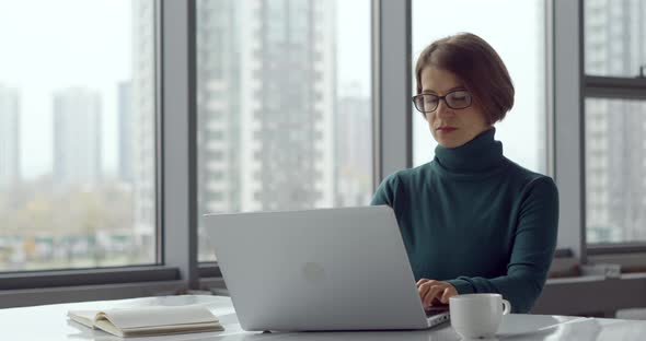 Business woman works at a laptop in a modern office. alt
