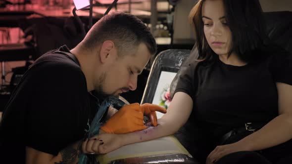 Tattoo Artist Makes a Tattoo Woman on a Arm, Works in Studio. Slow Motion alt