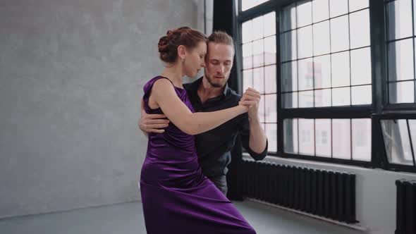 Shot of Woman Sitting on a Man's Leg Dancing a Tango in Grey Studio