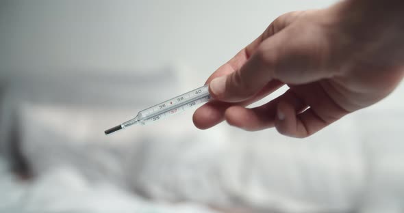 Male Hands Holding Analogue Thermometer with Very High Temperature alt