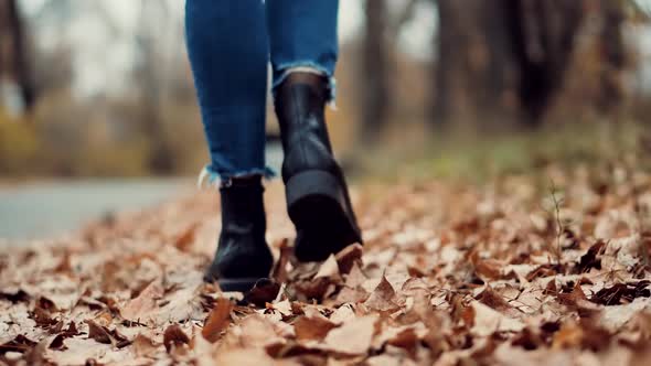 Woman Legs In Leather Shoes Walking On Vacation Holiday In Cold Autumn Day. Legs On Casual Sneakers. alt