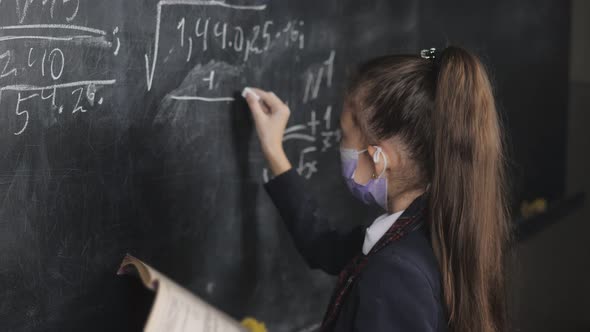 A High School Girl Writes Equations From a Textbook with Chalk on a Blackboard