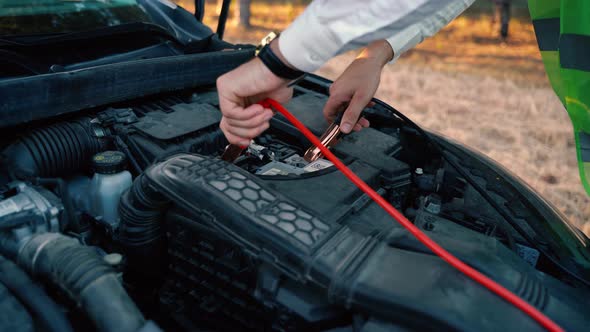 Close Up of a Man Charging Car Battery with Electricity Trough Jumper Cables alt