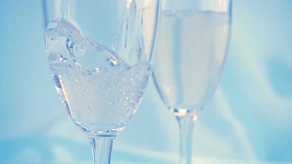 Sparkling wine is poured into a glass on a blue background. Slow motion. alt