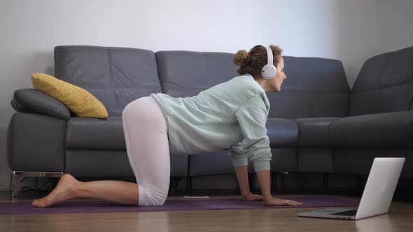 Young Caucasian Woman Practising Yoga Online at Home alt