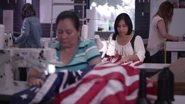 View of women with different ethnicities working in sewing shop alt