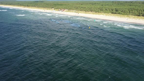 AERIAL: Rotating Shot of Surfers Kiting Power Kites on a Baltic Sea Waves