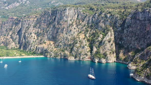 aerial drone panning up towards the large green mountains of Butterfly Valley while boats are anchor alt