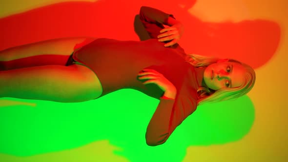 Sexy Woman in Tight Bodysuit Posing Attractively in Neon Lighting alt