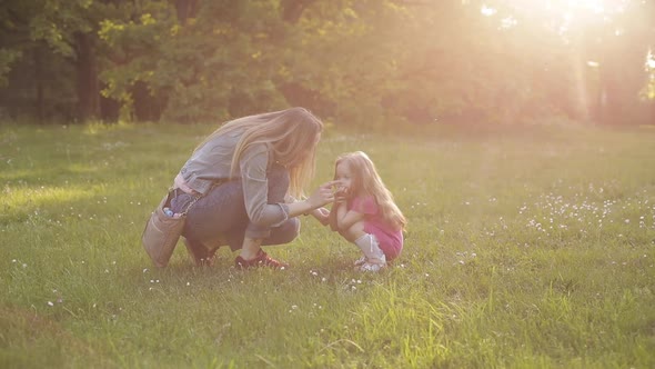 Little Kid with Long Hair Sitting on Front of Her Mother