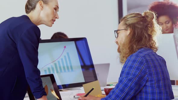 Executives interacting with each other while working at desk alt