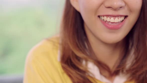 Asian woman feeling happy smiling and looking to camera while relax in her living room. alt
