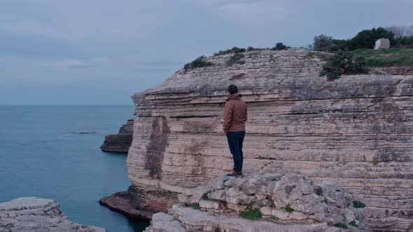 Orbiting Aroung Man Watching Sea From Top Of Rocks alt