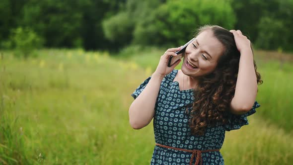 Closeup of Attractive Cheerful Young Caucasian Curly Woman Walking on and Using Modern Smartphone