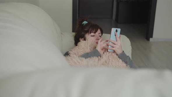 Woman Lies on the Couch and Uses the Phone Instead of a Book To Read