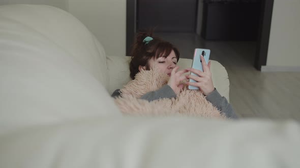 Woman Lies on the Couch and Uses the Phone Instead of a Book To Read alt