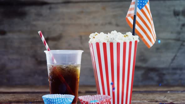 Popcorn, confectionery and drink on wooden table alt